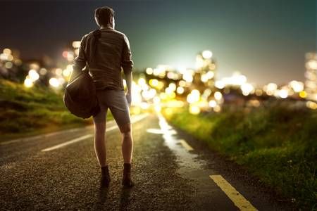 77028599-guy-walks-towards-city-lights-on-a-country-road.jpg